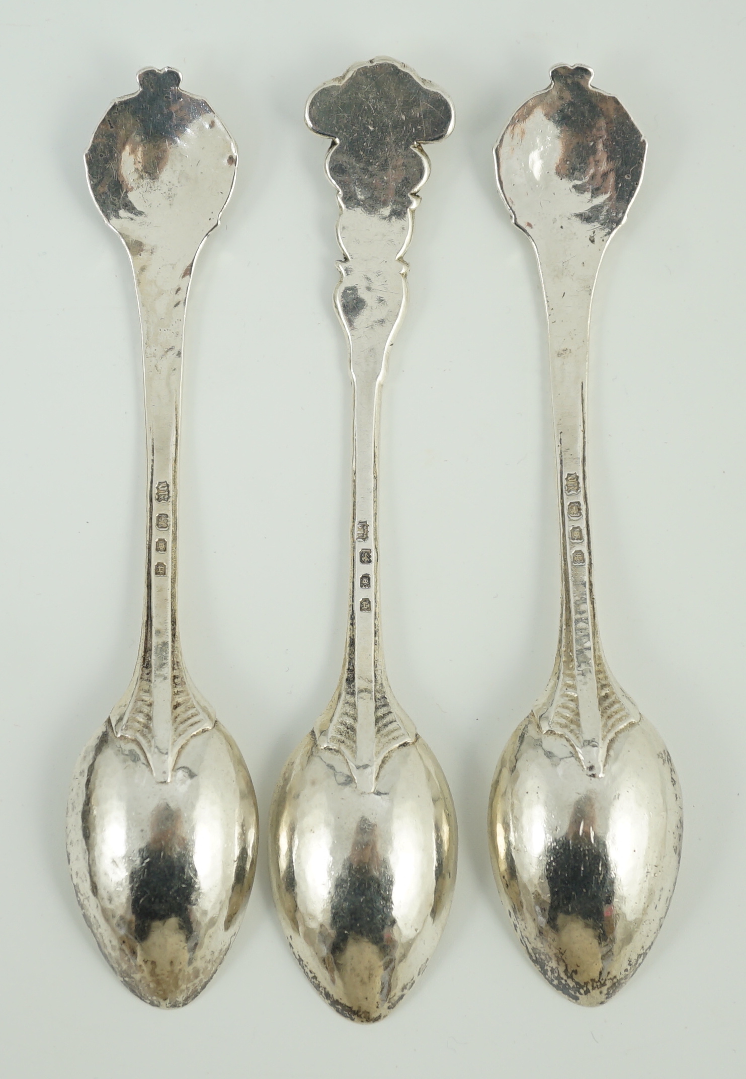 A cased set of three George V Arts & Crafts planished silver spoons by Omar Ramsden